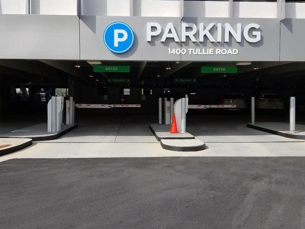 Controlled access parking garage with security gate arms and authorized entry.
