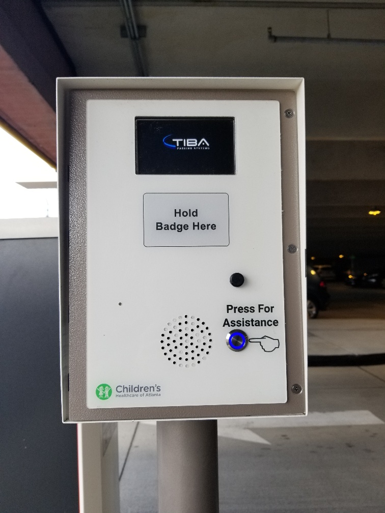 Parking garage controlled access system with badge scanned access and button to speak to a person for permission to gain entry.