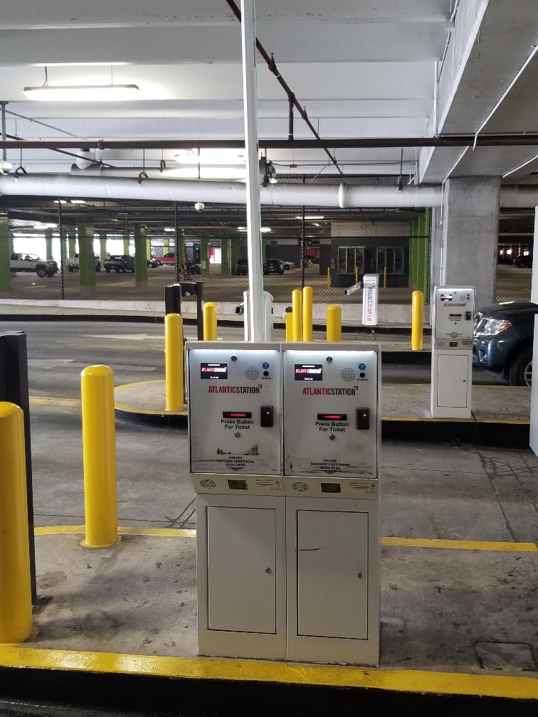 Two ticketing systems seen side-by-side at the entrance of a controlled parking garage.