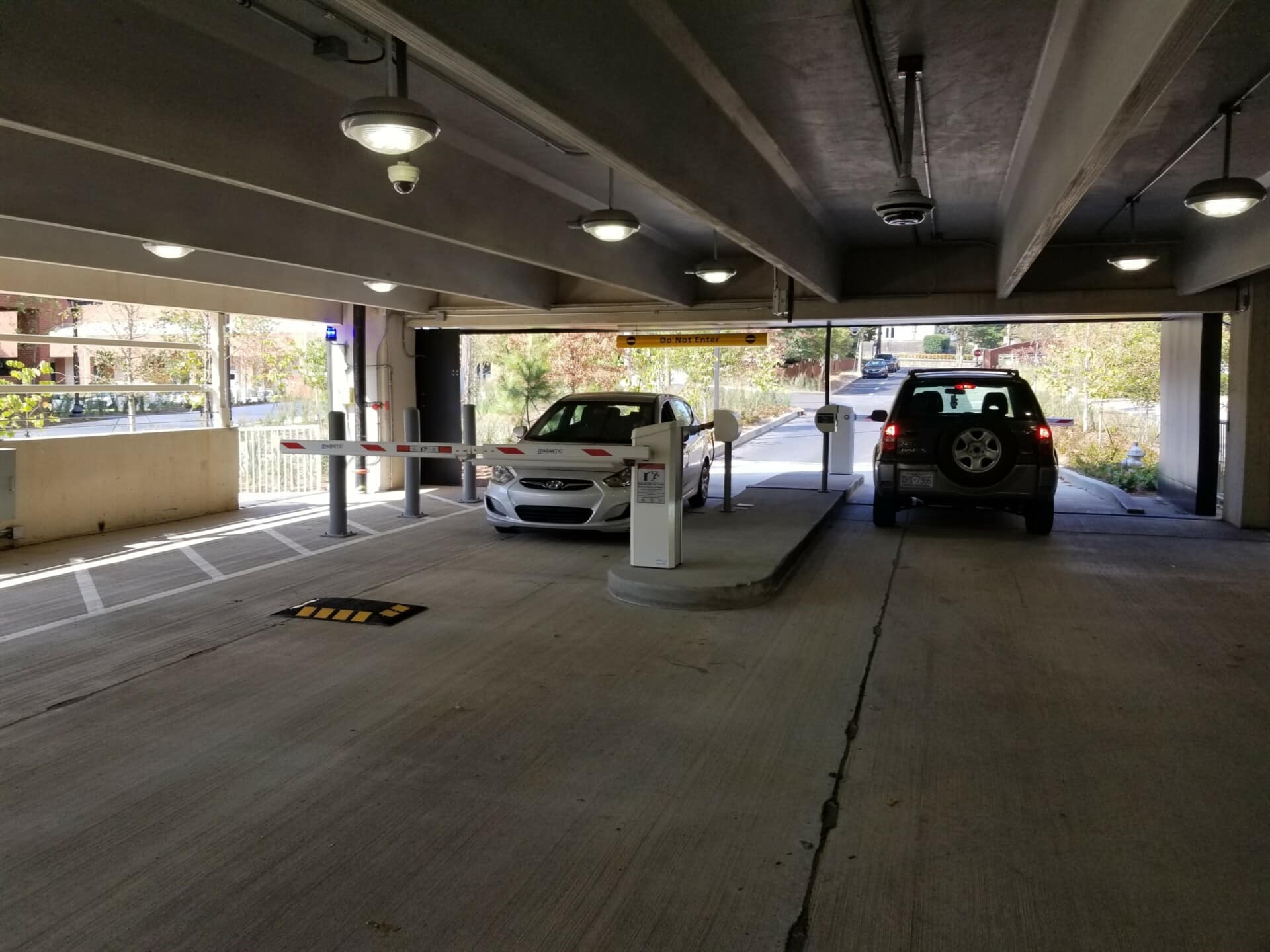 One car enters the gated access parking area and another exits.