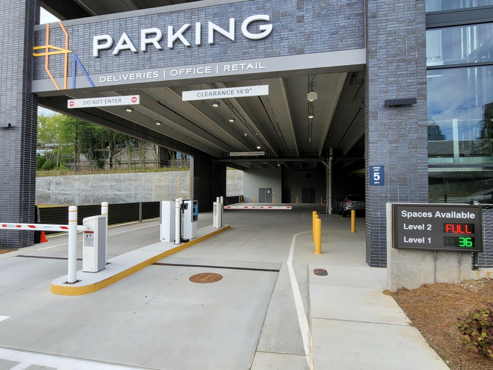 Parking access controlled with gate entry and with a sign sharing levels and parking spaces open.