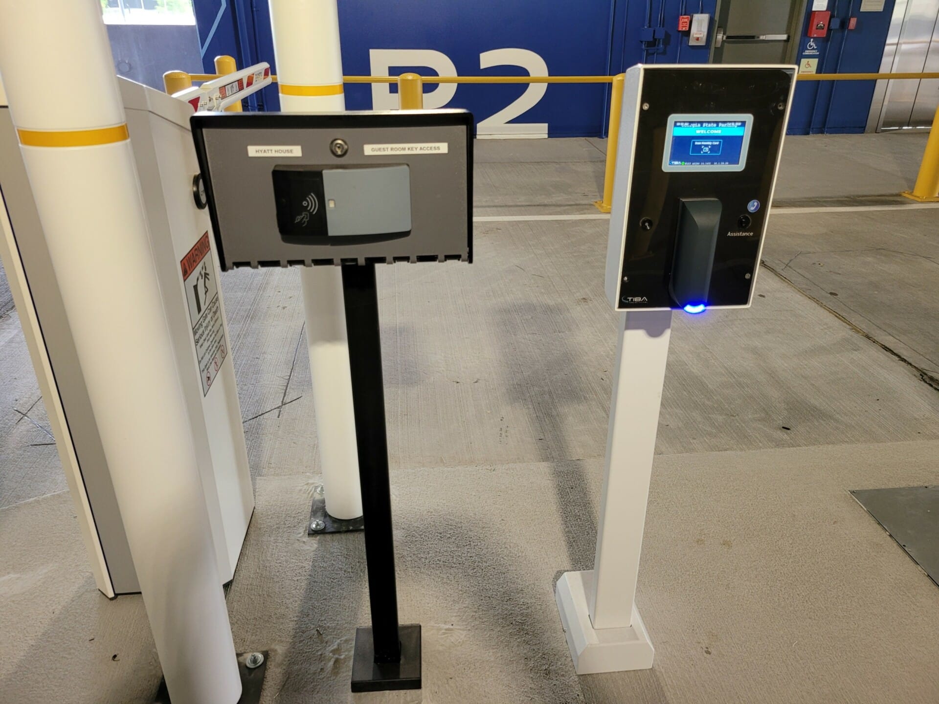 Blue light shines on keycard scanner for secure parking entry.