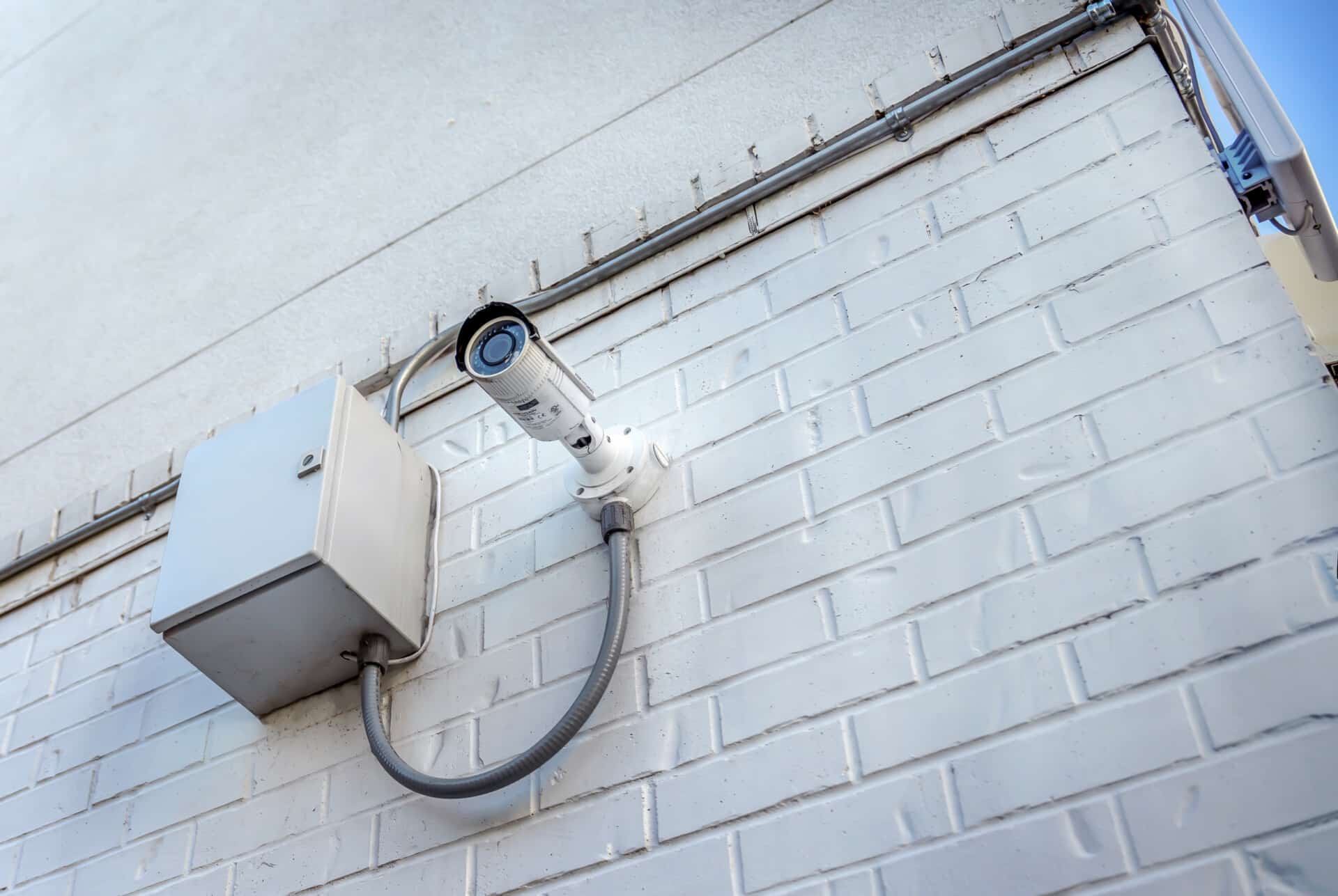Underside view of a security camera and control box installed outside a building.