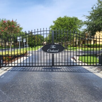 Close view of a grilled black gate with "the Orchard" written in a fancy font on the front