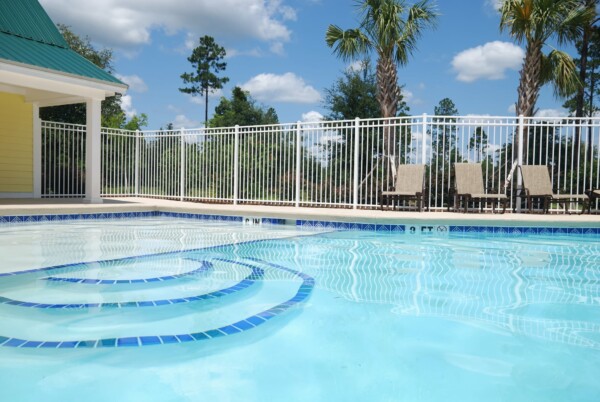 Community pool with white perimeter fencing.