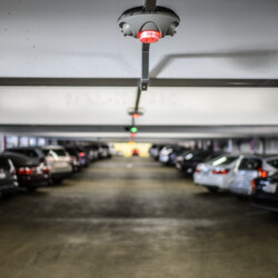 Parking garage parking sensor with License Plate Recognition above vehicles.