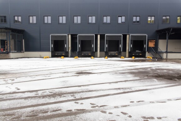 Snow on the ground in front of delivery doors outside of a distribution center.