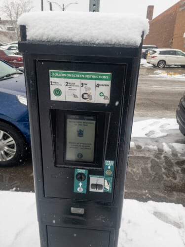 Parking Area Pay Station with Snow in Front of a Parking Area.