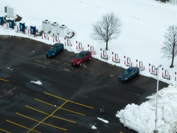 Parking lot with snow around the perimeter, electric car charging stations to one side.
