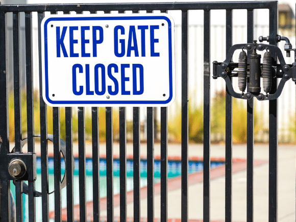 Closed pool gate with signage that says keep gate closed